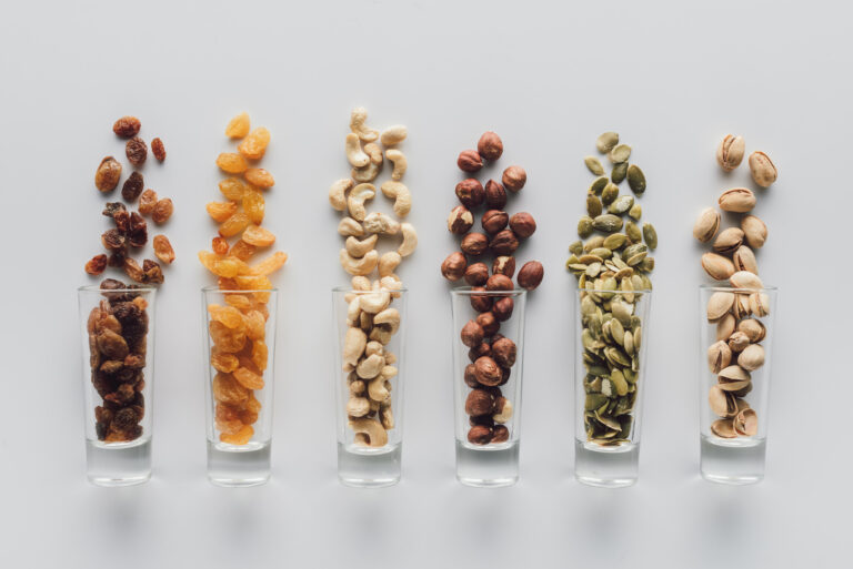 Assorted delicious nuts and raisins in glass cups isolated on white background