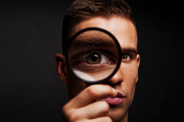 Man with magnifier on dark background