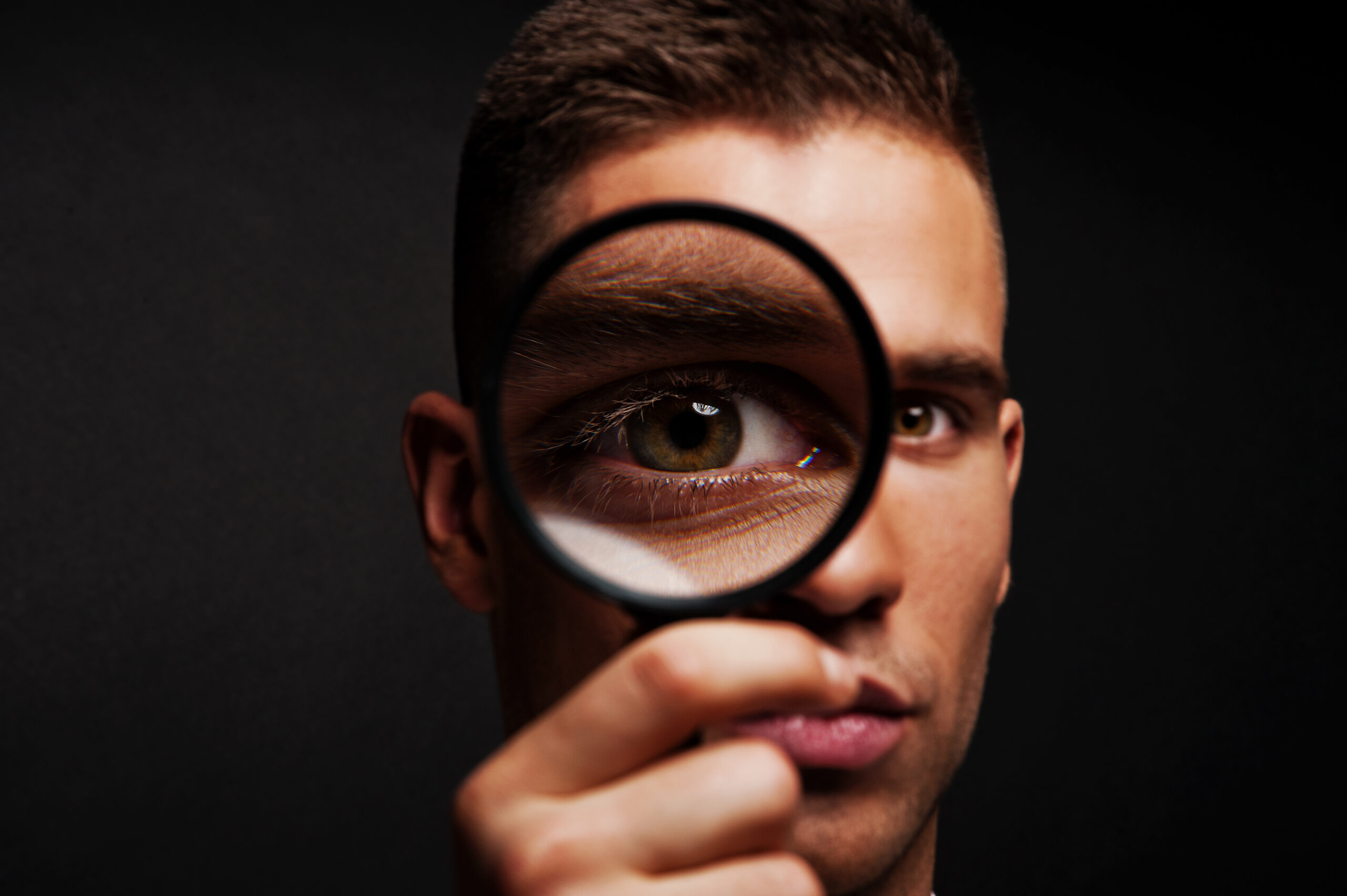 Man with magnifier on dark background